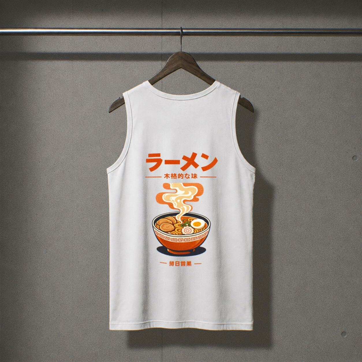 Camiseta de tirantes blanca colgada de una percha de madera sobre una pared gris texturizada. En la parte delantera lleva un estampado de un bol de ramen con texto japonés en naranja arriba y abajo.
